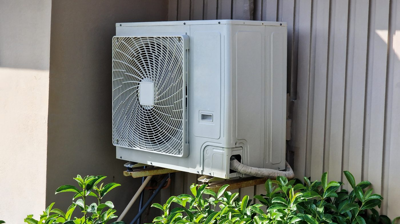 Outdoor ductless mini-split condenser unit mounted beside a home.