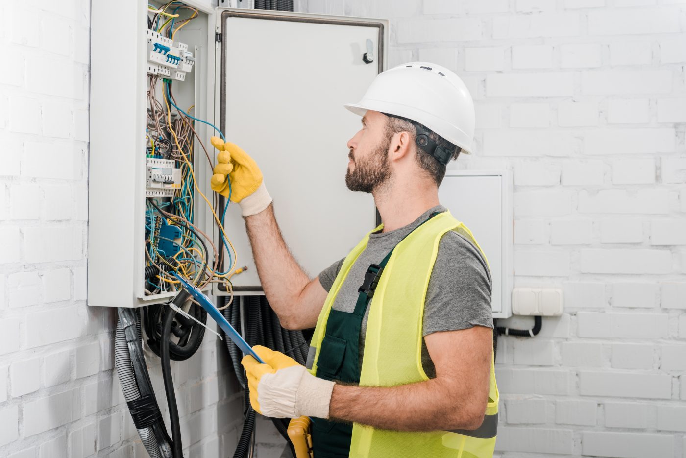 Electrician working on a commercial electrical panel, representative of NCIS commercial services.
