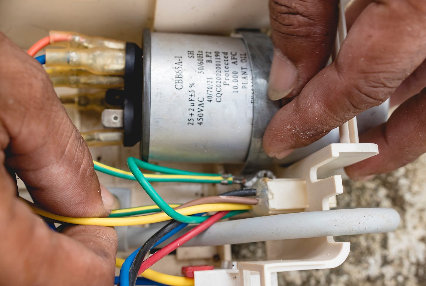Technician servicing a generator capacitor during annual maintenance.