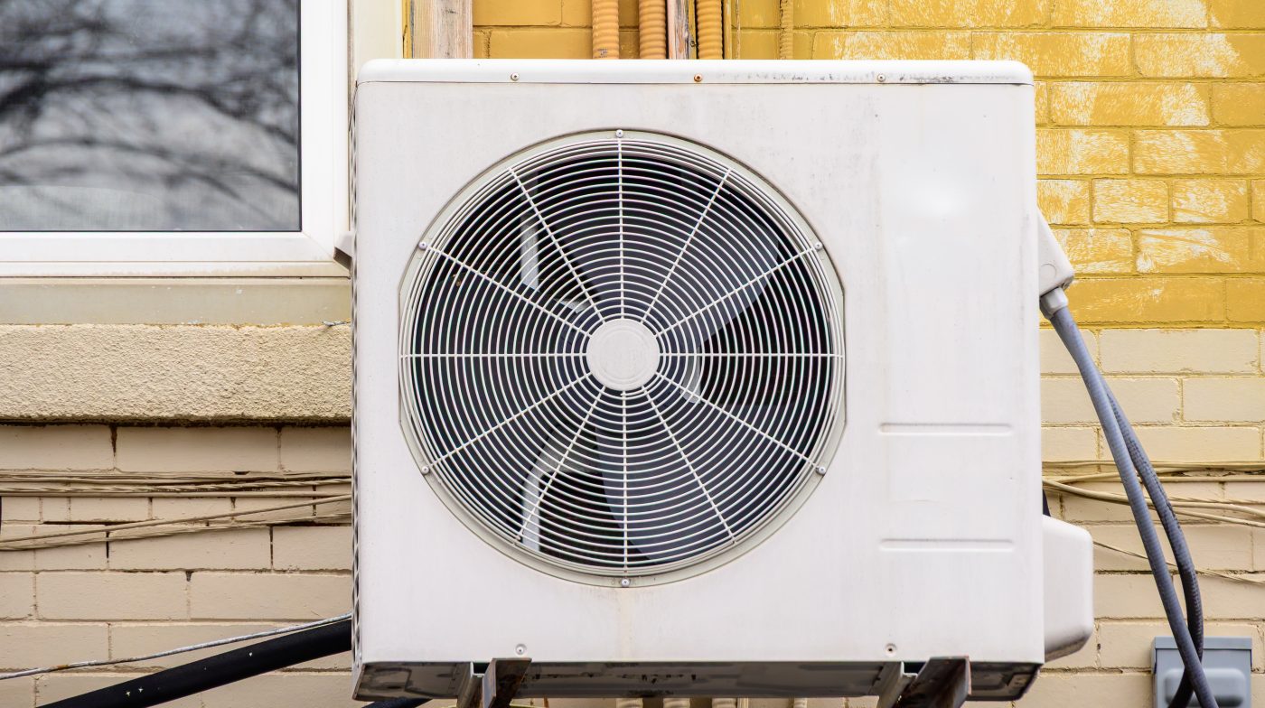 Outdoor ductless mini-split heat pump condenser mounted on the exterior wall of a home.