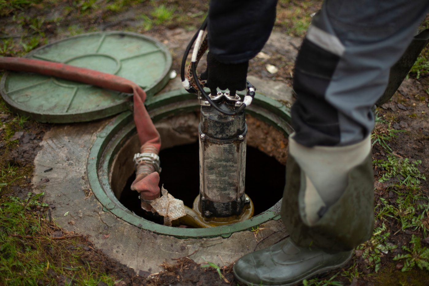 Technician servicing a sewer line through an open manhole, representative of drain and sewer service.